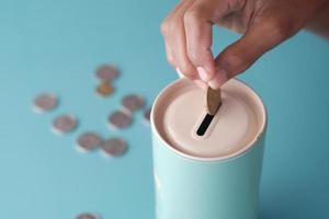 Jeune homme économisant des pièces dans un pot situé blanc photo