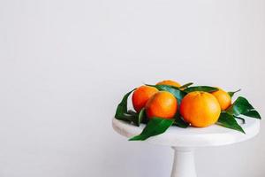 mandarines orange sur fond gris dans le décor du nouvel an avec des pommes de pin brunes et des feuilles vertes. décoration de noël avec des mandarines. délicieuse clémentine sucrée. photo