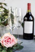 composition avec verre, fleurs et bouteille de vigne sur fond de béton gris. photo
