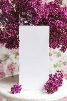 drap blanc dans un beau lilas en fleurs sur un support blanc sur un fond floral. carte de voeux, place pour le texte, maquette photo