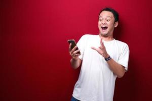 jeune homme asiatique choqué quand il regarde et pointe un smartphone photo