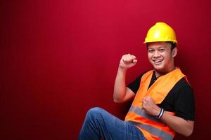 heureux jeune travailleur asiatique excité et souriant levant le bras pour célébrer le succès ou la réussite. photo