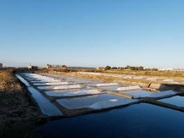 coucher de soleil sur les champs de sel après une journée complète de ramassage du sel. belles couleurs vives. champs de sel à castro marim, portugal. extraction de sel. photo