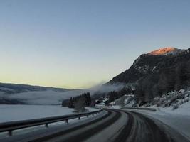 conduire au lever du soleil à travers les montagnes et les forêts en norvège. photo