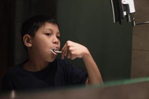 garçon asiatique se brosser les dents dans la salle de bain photo