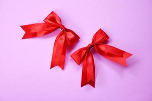 noeud de ruban rouge sur fond rose - deux noeuds cadeau en épingle à cheveux vacances parfaites faites à la main photo