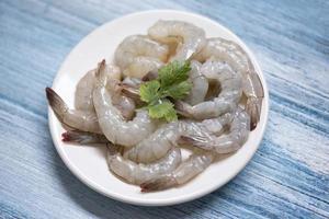 crevettes fraîches ou crevettes , fruits de mer - crevettes crues sur plaque blanche et fond en bois pour la cuisson photo