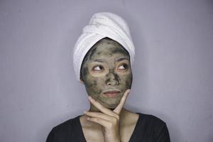 une femme asiatique pensait et rêvait lorsqu'elle utilisait un masque de beauté photo