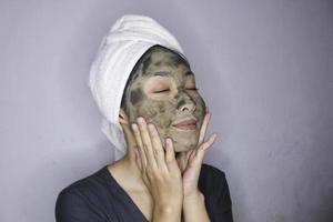 sourire des femmes asiatiques souriantes quand elle utilise un masque de beauté photo