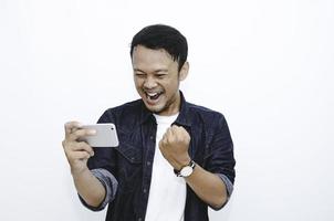 sourire et visage heureux d'un jeune homme asiatique en jouant au téléphone en main. photo