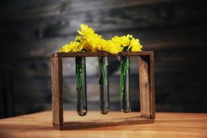 marguerites jaune vif dans un vase en verre sur une épée en bois. photo