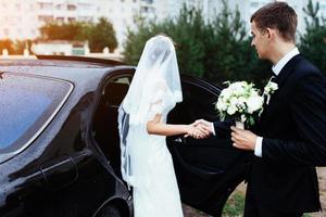 heureuse mariée et le marié près de la voiture. photo
