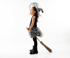 Portrait petite fille asiatique s'habiller en sorcière mignonne pour costume d'halloween avec balai photo