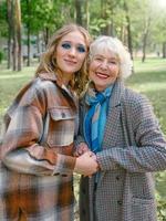 femme senior avec jeune fille marchant en plein air au printemps. famille, génération, soins, amour, concept de vaccination photo