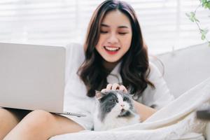 jeune femme d'affaires asiatique travaillant et jouant avec un chat photo