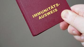 carte d'identité ou passeport allemand - main tenant une maquette de certificat d'immunité européen document de voyage