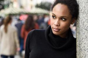 jeune femme noire avec une coiffure afro debout en arrière-plan urbain photo