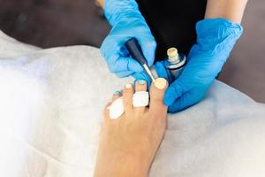 esthéticienne donnant une pédicure peignant les ongles de son client dans un centre de beauté. photo