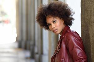 jeune femme noire avec une coiffure afro debout en arrière-plan urbain photo