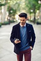 homme dans la rue en tenue de soirée avec smartphone à la main. photo