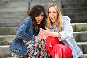 deux jeunes femmes à la recherche d'une chose géniale sur leur téléphone intelligent photo