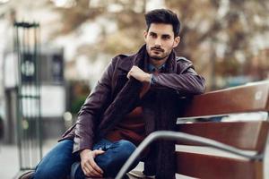 jeune homme réfléchi assis sur un banc urbain. photo