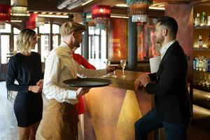 barman servant un cocktail sur le comptoir pour les clients photo