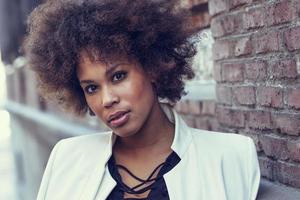 jeune femme noire avec une coiffure afro debout en arrière-plan urbain photo
