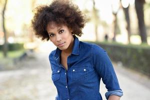 jeune femme noire avec une coiffure afro debout en arrière-plan urbain photo