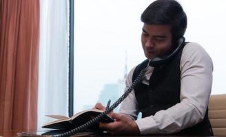 un jeune homme d'affaires surveille et suit les tâches dans son bureau photo