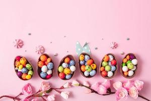 Oeufs de pâques en chocolat et décor plat pour les enfants concept d'oeufs de chasse de pâques sur fond rose. bonbons en forme d'oeuf photo