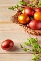 oeufs de pâques dorés dans un panier en osier sur un fond en bois. photo