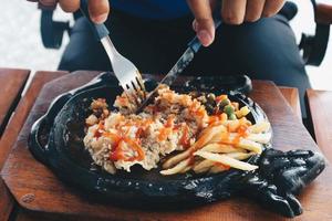 une main a coupé une plaque chauffante de steak croustillant au poulet avec sauce barbecue et pommes de terre photo