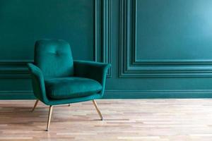 belle salle intérieure de luxe classique bleu vert propre dans un style classique avec fauteuil vert doux. chaise bleu-vert antique vintage debout à côté du mur émeraude. conception de maison minimaliste. photo