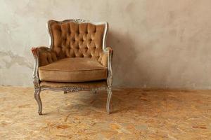 belle salle intérieure propre de luxe classique de style grunge avec fauteuil baroque marron. Chaise marron-gris antique vintage debout à côté du mur. conception de maison minimaliste. photo