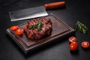 steak de boeuf ribeye grillé, herbes et épices sur une table sombre photo