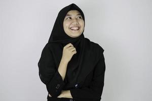 geste heureux et rêvassant jeune femme islamique asiatique portant un foulard. photo
