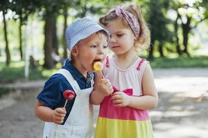 des enfants heureux goûtent des bonbons sur un bâton photo