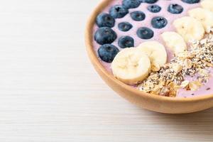 bol de smoothie au yaourt ou au yaourt avec baies bleues, banane et granola photo