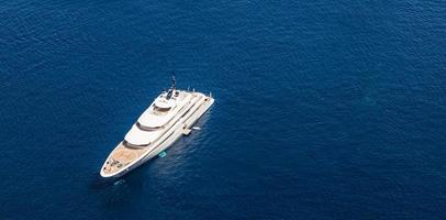 drone aérien photo ultra large d'un yacht de luxe avec pont en bois ancré près du port. yacht à moteur privé de luxe naviguant en mer