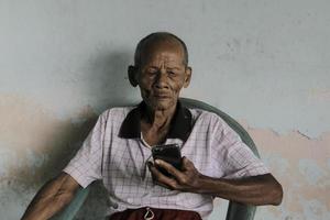 un portrait d'un vieux grand-père indonésien appelant un smartphone. photo