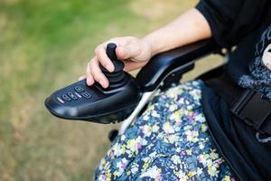 femme asiatique femme patiente sur fauteuil roulant électrique avec joystick et télécommande à l'hôpital de soins infirmiers, concept médical solide et sain photo