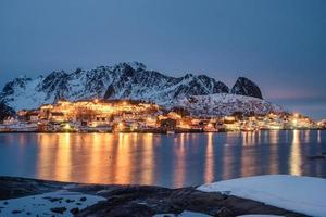 Illumination du village de pêcheurs avec chaîne de montagnes sur le littoral en hiver aux îles Lofoten photo