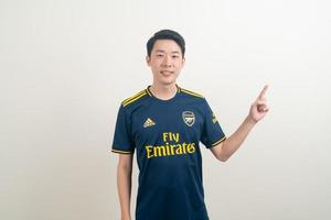 bangkok, thaïlande - 27 novembre 2021 - jeune homme asiatique portant une chemise d'arsenal avec un fond blanc. photo