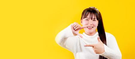 une fille asiatique qui a un sourire joyeux, amusant et brillant. expression des yeux aimants bonne vie et bonheur au travail, détente, sur fond jaune photo