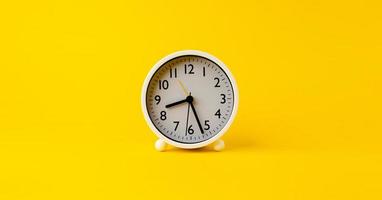 réveil blanc l'horloge indique l'heure de se réveiller le matin. posé sur fond jaune photo