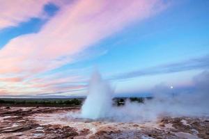éruption du geyser de strokkur en islande. des couleurs fantastiques brillent à travers photo
