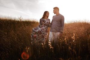 jeune couple se reposant dans la nature dans un champ. couple au coucher du soleil photo