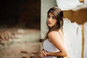 portrait en gros plan d'une jeune fille brune mignonne posée sur un lieu abandonné. photo