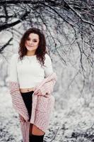 fond de fille brune bouclée chute de neige, porter sur un pull en tricot chaud, une mini jupe noire et des bas de laine. modèle sur l'hiver. portrait de mode par temps neigeux. photo tonique instagram.